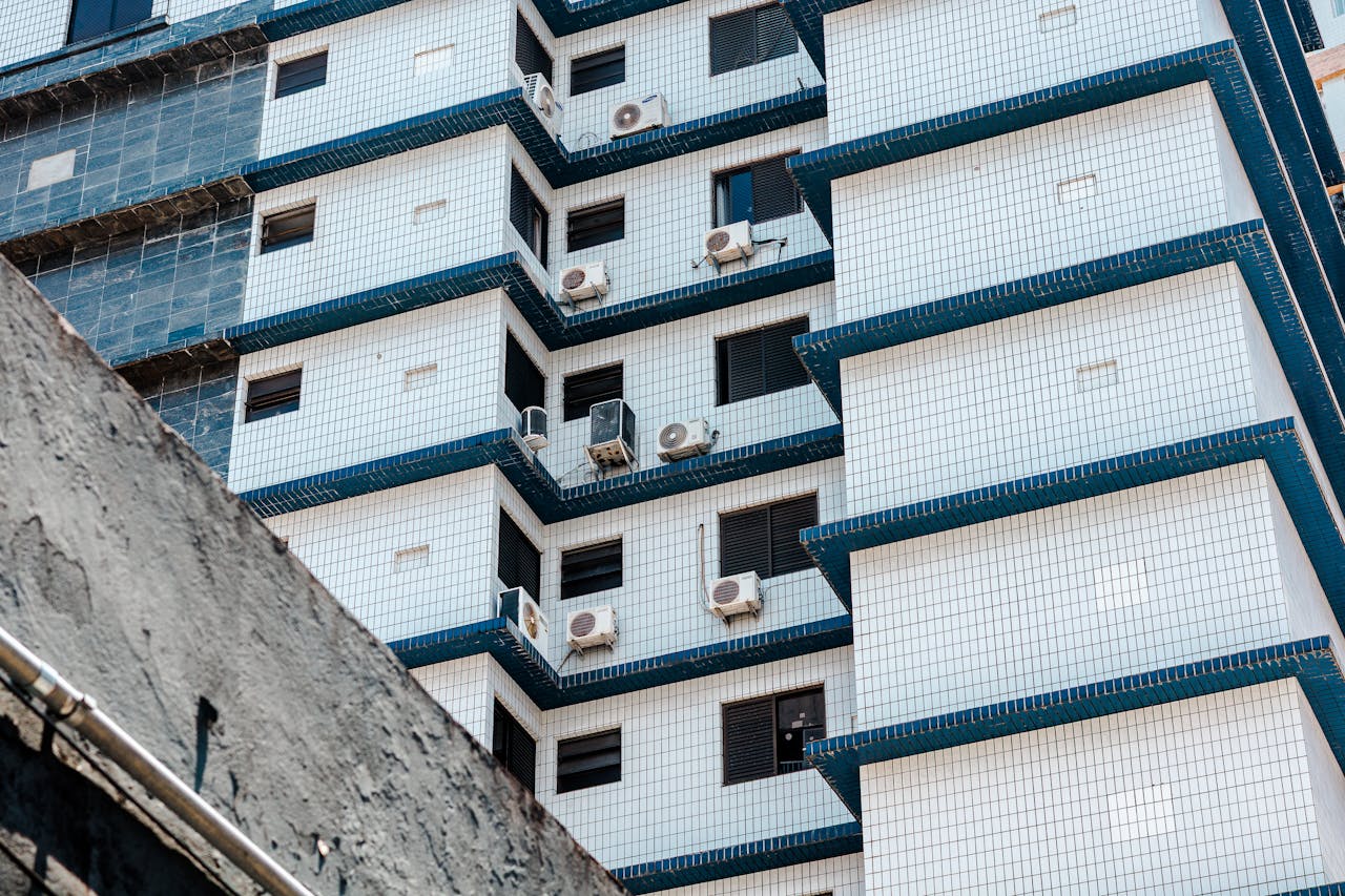Abstract view of a tiled high-rise building fa1ade featuring multiple air conditioning units.
